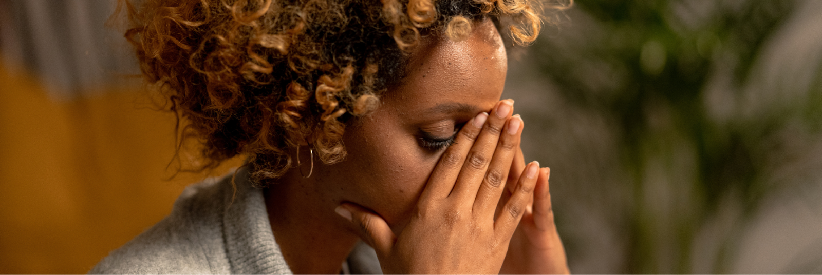 The woman, overwhelmed with stress, presses her hands to her face and forehead in a desperate attempt to calm herself. 